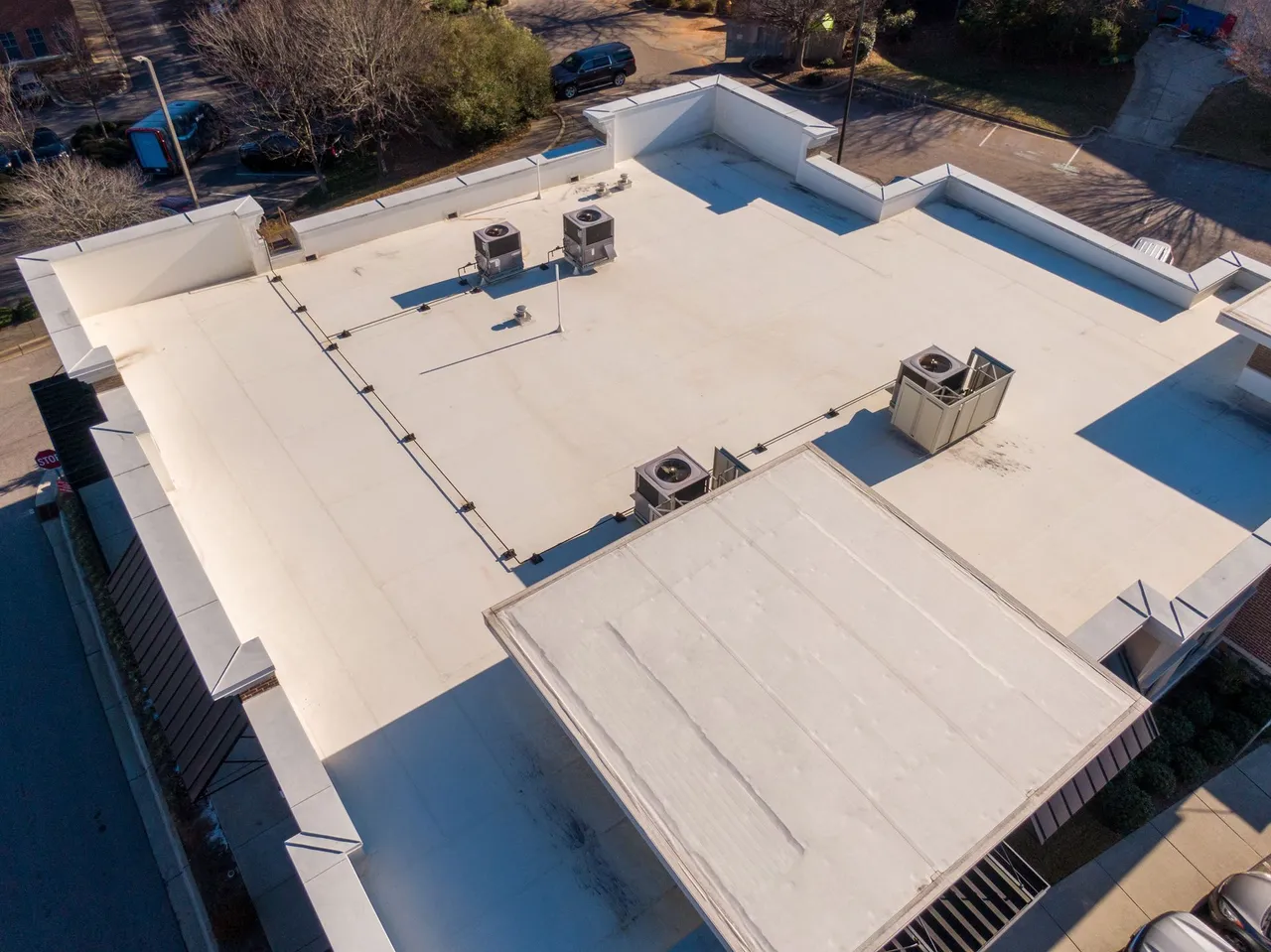 Aerial view of a flat white commercial roof with HVAC units.