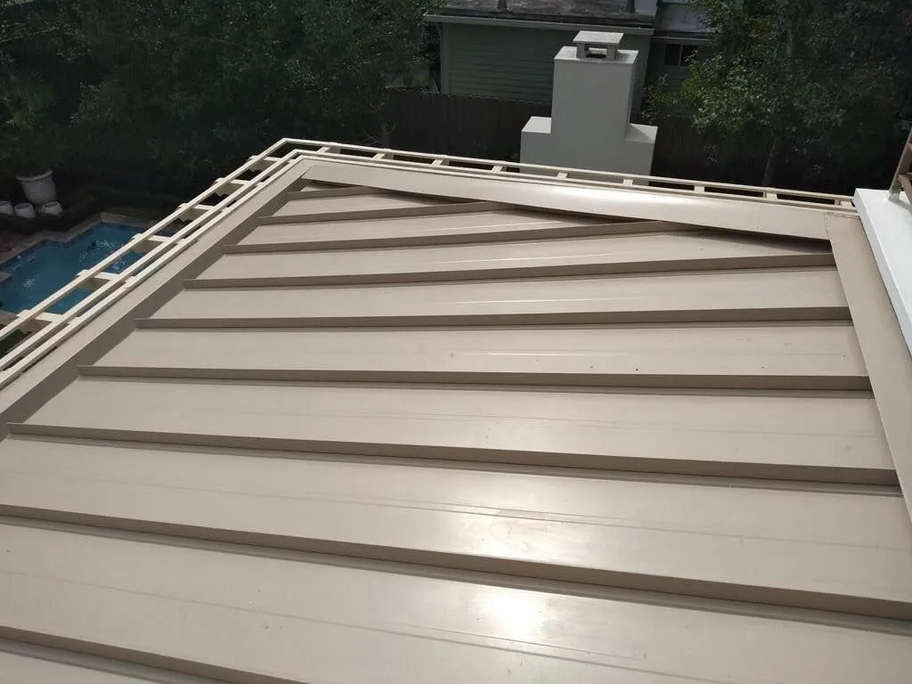 Beige metal roof with horizontal lines, a chimney in the background, and a pool visible to the left.