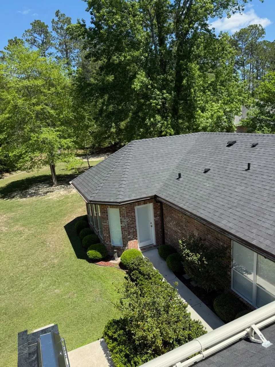Gray shingle roof of a house with a chimney and part of a green roof visible.