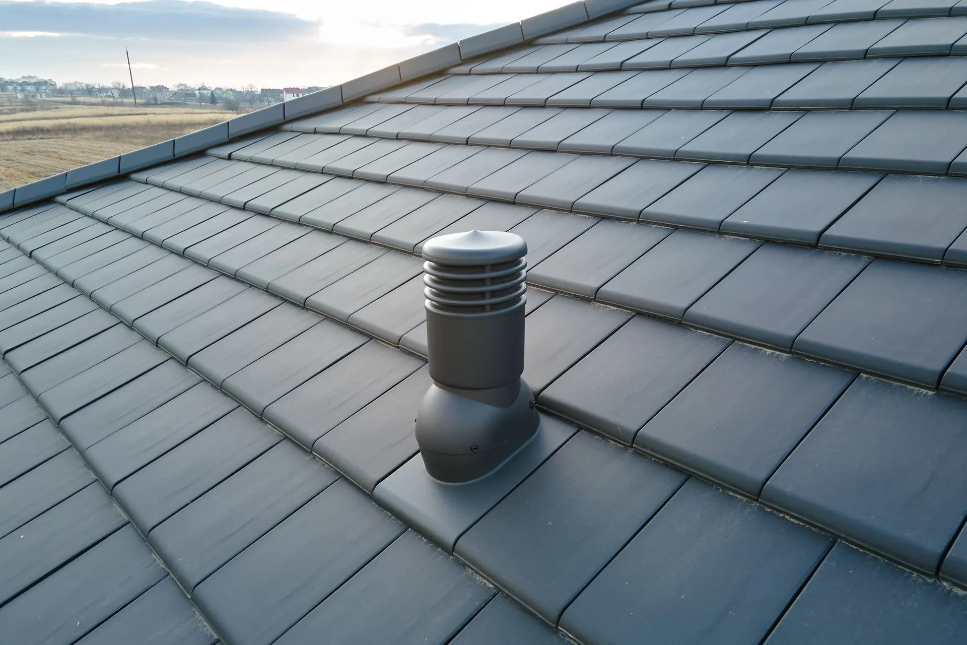 Dark gray tile roof with a black vent.